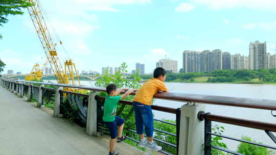 两个小孩在江边爬栏杆看风景