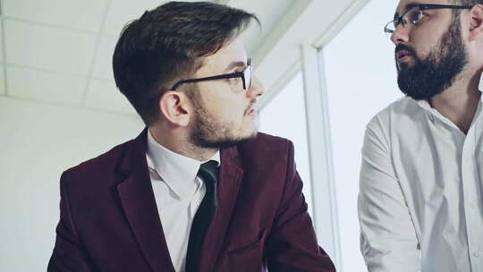 同事讨论工作问题两个戴眼镜的大胡子年轻人和穿商务夹克的女人