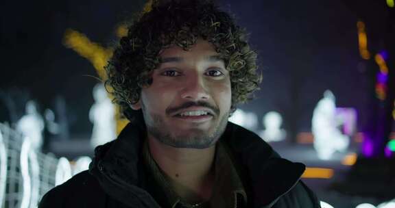 冬夜，年轻的印度男子站在户外，背景是花环