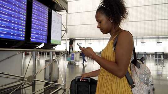 年轻的拉丁女性旅行者在机场使用电话检查她