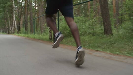 男人在林间公路上奔跑腿部特写