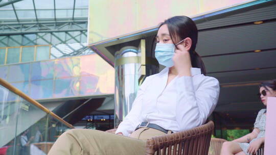 青年女人摘掉口罩坐在咖啡馆里视频素材模板下载