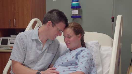 一名男子在怀孕妻子躺在医院病床上时抚摸她