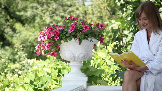 女人穿着浴袍在花园里看书