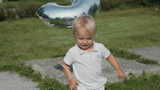 男孩拿着气球在草地上奔跑