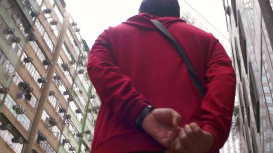 在高楼中背手行走的穿红衣服的人视频素材模板下载