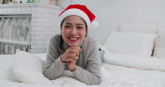 美女戴着圣诞帽趴在床上开心对镜头讲话祝福