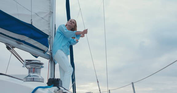 一个穿蓝色衣服的女人站在帆船上看风景
