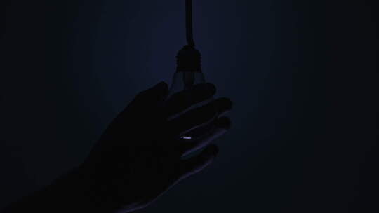 电线上的复古灯在深蓝色背景下在男性手上发光和闪烁