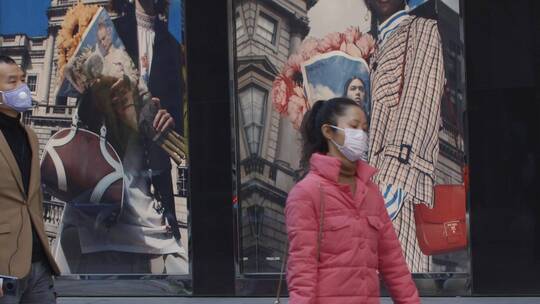 疫情下的成都街头行人戴口罩走过广告牌