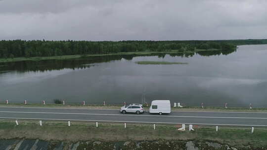加拿大，一辆装有露营拖车的汽车沿着大坝穿过一条河。无人机