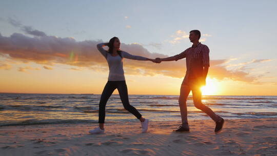 夫妇手拉手走在日落的海滩上