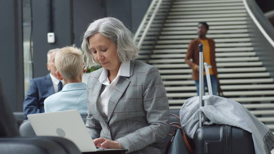 老年女商人在机场使用个人电脑认真工作