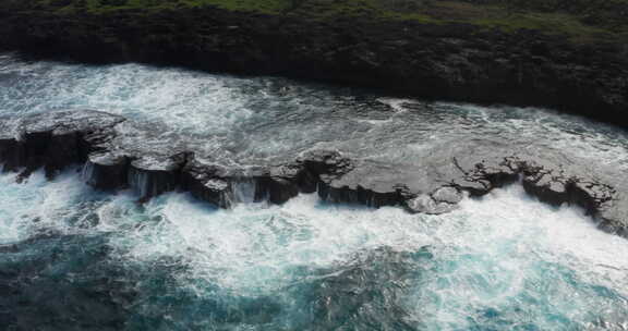 航拍海浪在暴风雨前撞击荒岛的岩石悬崖。