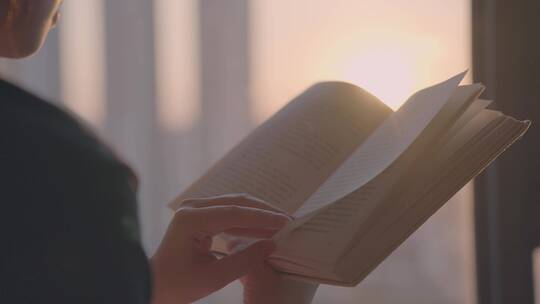 女孩在房间落地窗前看书，夕阳逆光唯美光晕视频素材模板下载