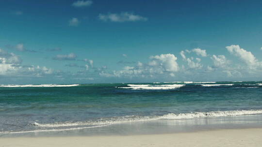 蓝天下的海浪冲击着海滩