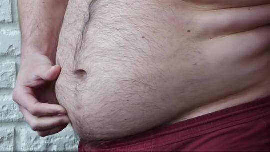 肥胖的男人。一个超重的男人在展示大肚子