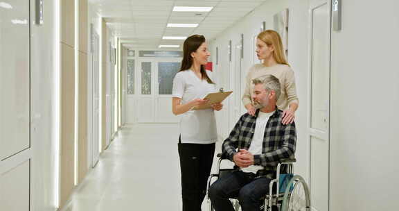 医院轮椅上的中年男子与护士和同伴中年男子