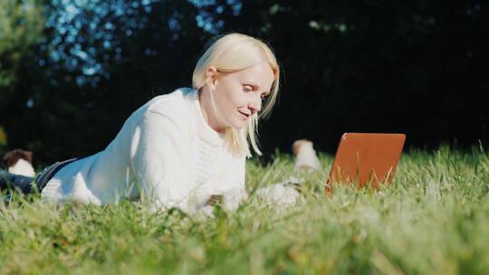 女士躺在草地玩电脑