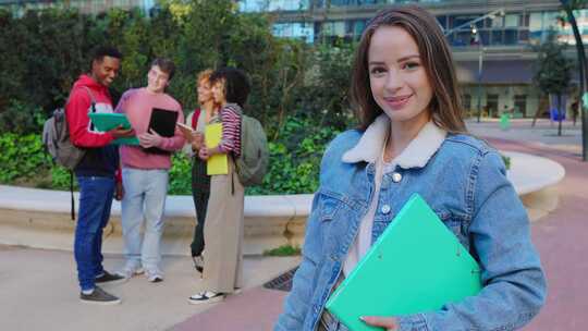 微笑的大学生在校园里拿着活页夹，背景是朋