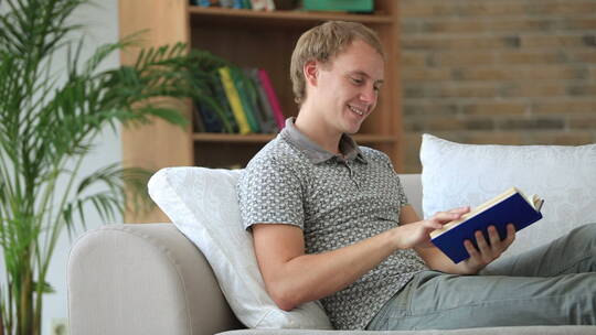 男人坐在沙发上看书微笑