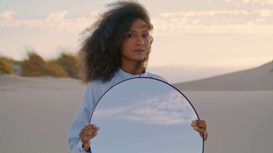 夏季特写时，女艺术家在沙漠中摆姿势镜子