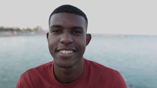 微笑的巴西男子在海边看着相机的特写肖像