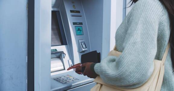 女人在自动取款机前输入密码