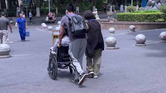 家属推坐轮椅病人医院外行走