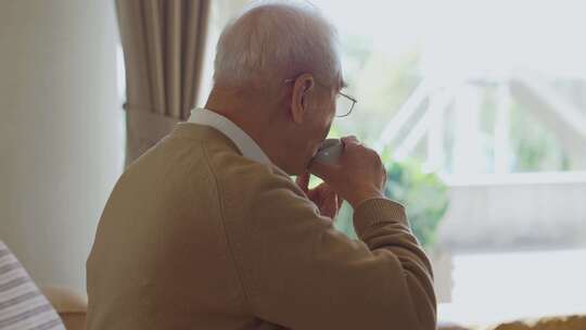 老人坐在窗边喝茶的悠闲生活场景