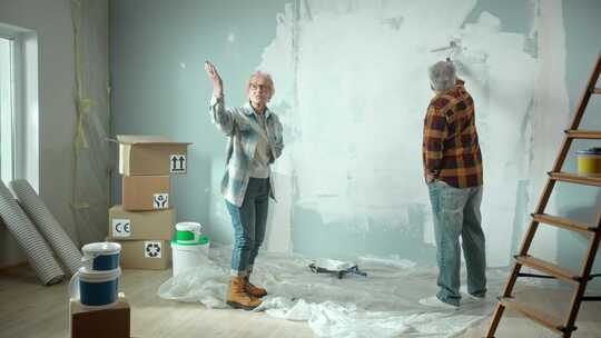 老人用油漆滚筒用白色油漆粉刷墙壁