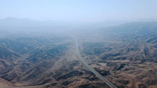航拍两侧山峰环绕的荒野沙漠高速公路