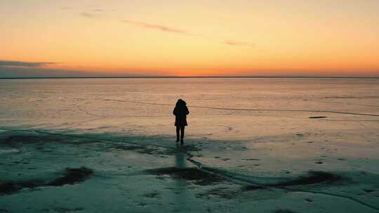 航拍夕阳下人物在冬天冰面前行