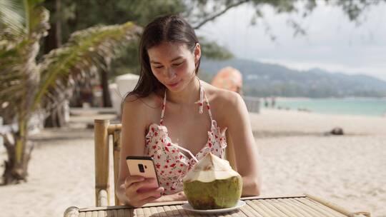 女人在海滩上喝椰子汁视频素材模板下载