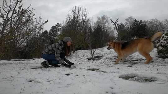 一个女人在雪地里和她的狗玩耍