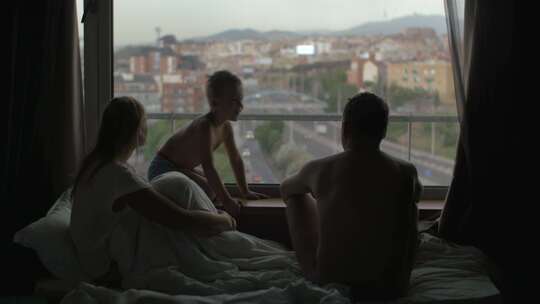 一家人坐在床上看着窗外聊天