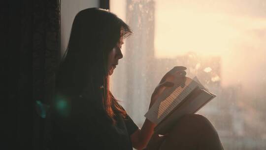 夕阳下的窗边女孩坐在地板上看书