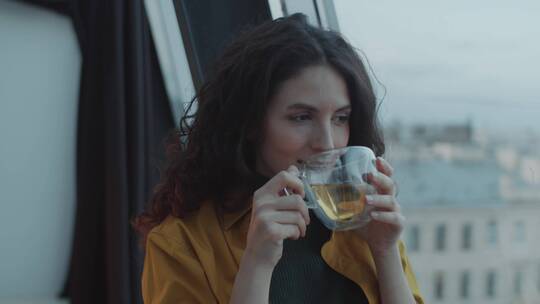 女人惬意的站在窗边喝茶水视频素材模板下载