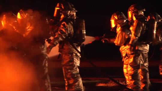 穿着防护服的消防员在夜间扑灭大火