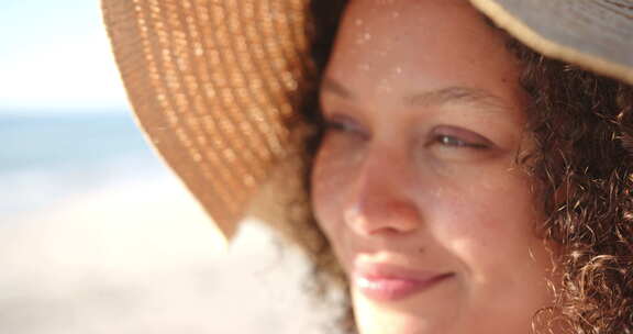 一个年轻的混血女人在海滩上戴着太阳帽