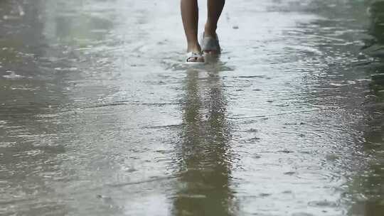 儿童从下着雨的积水路上走过