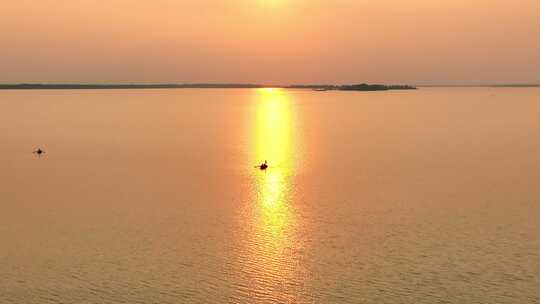 航拍暖色夕阳下湖面上渔船