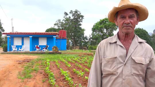 一名古巴农民站在农场的农舍前