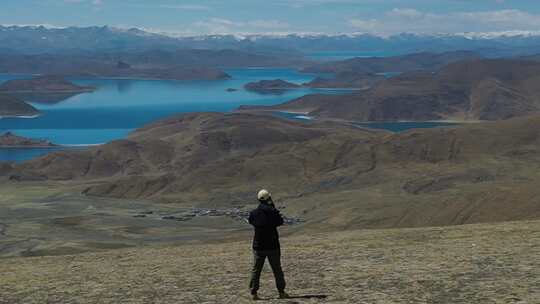 4k男人在航拍西藏蓝色羊湖雪山视频素材模板下载