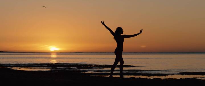 女孩在黄昏的沙滩上舞蹈
