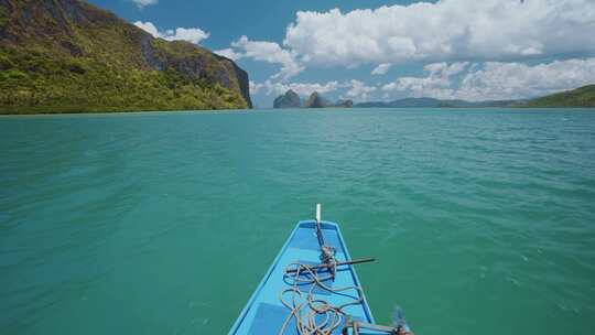 跳岛之旅蓝色小船悬停在异国岩溶石灰岩之间开阔的蓝色海洋表面