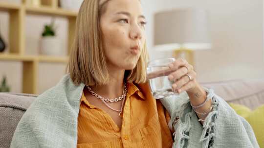 女性在家中手持水杯仰头吃药