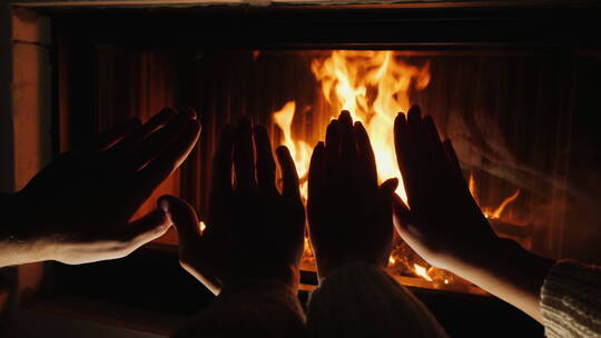 两双手在壁炉的炉火前取暖