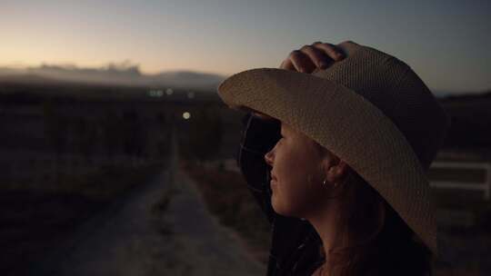 戴草帽女子黄昏时眺望远方
