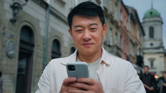 微笑的男人在手机上浏览社交媒体快乐的男性游客通过互联网预订旅游使用